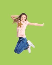 Happy cute girl jumping on light green background