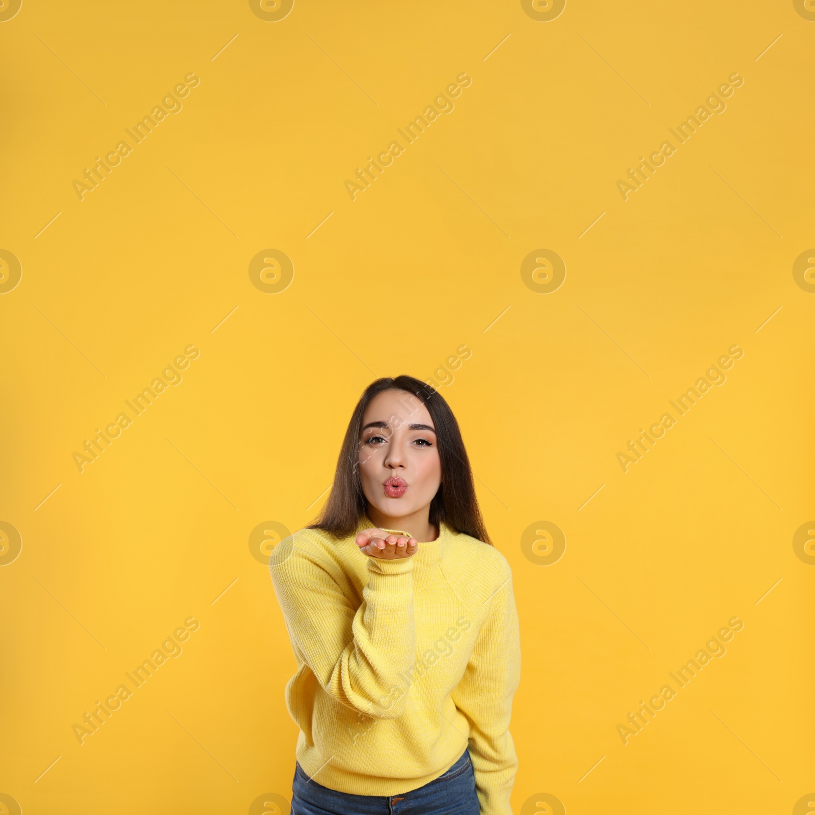 Photo of Beautiful young woman wearing warm sweater on yellow background. Space for text