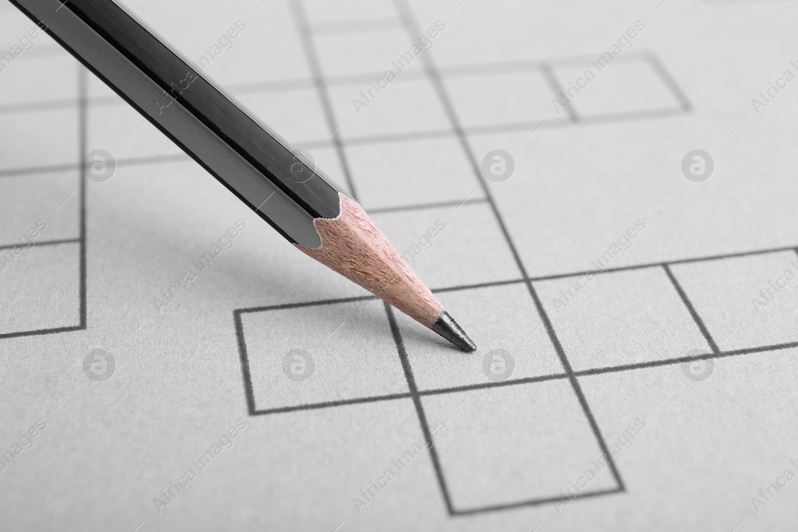 Photo of Pencil and blank crossword, closeup view. Intellectual entertainment