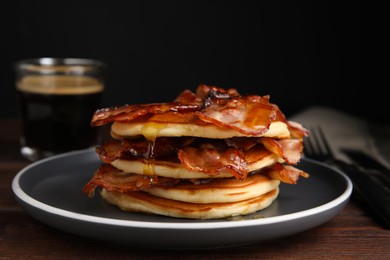 Delicious pancakes with maple syrup and fried bacon on wooden table