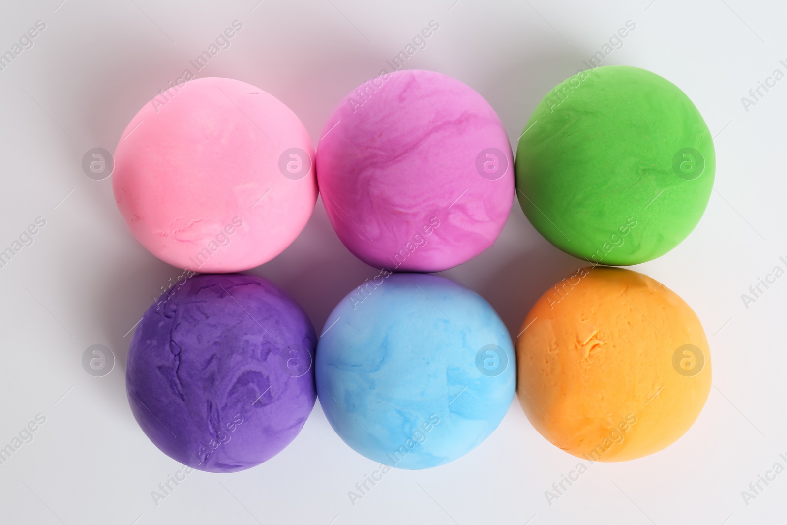 Photo of Different color play dough balls on white background, top view