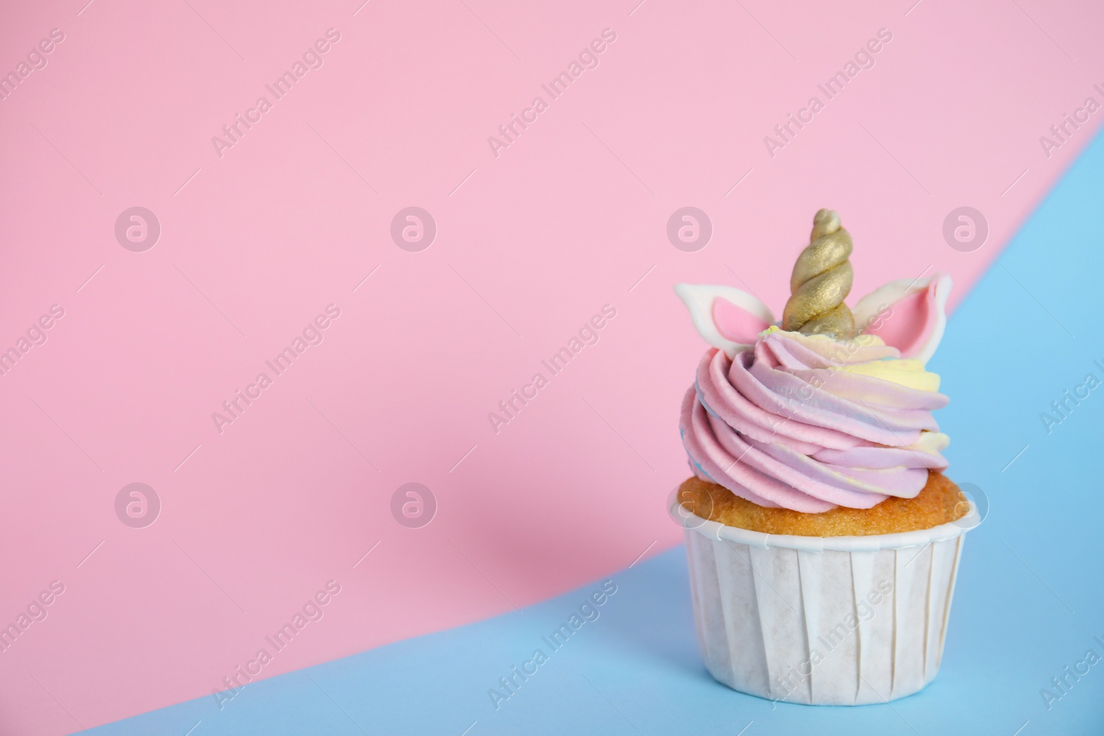 Photo of Cute sweet unicorn cupcake on color background. Space for text