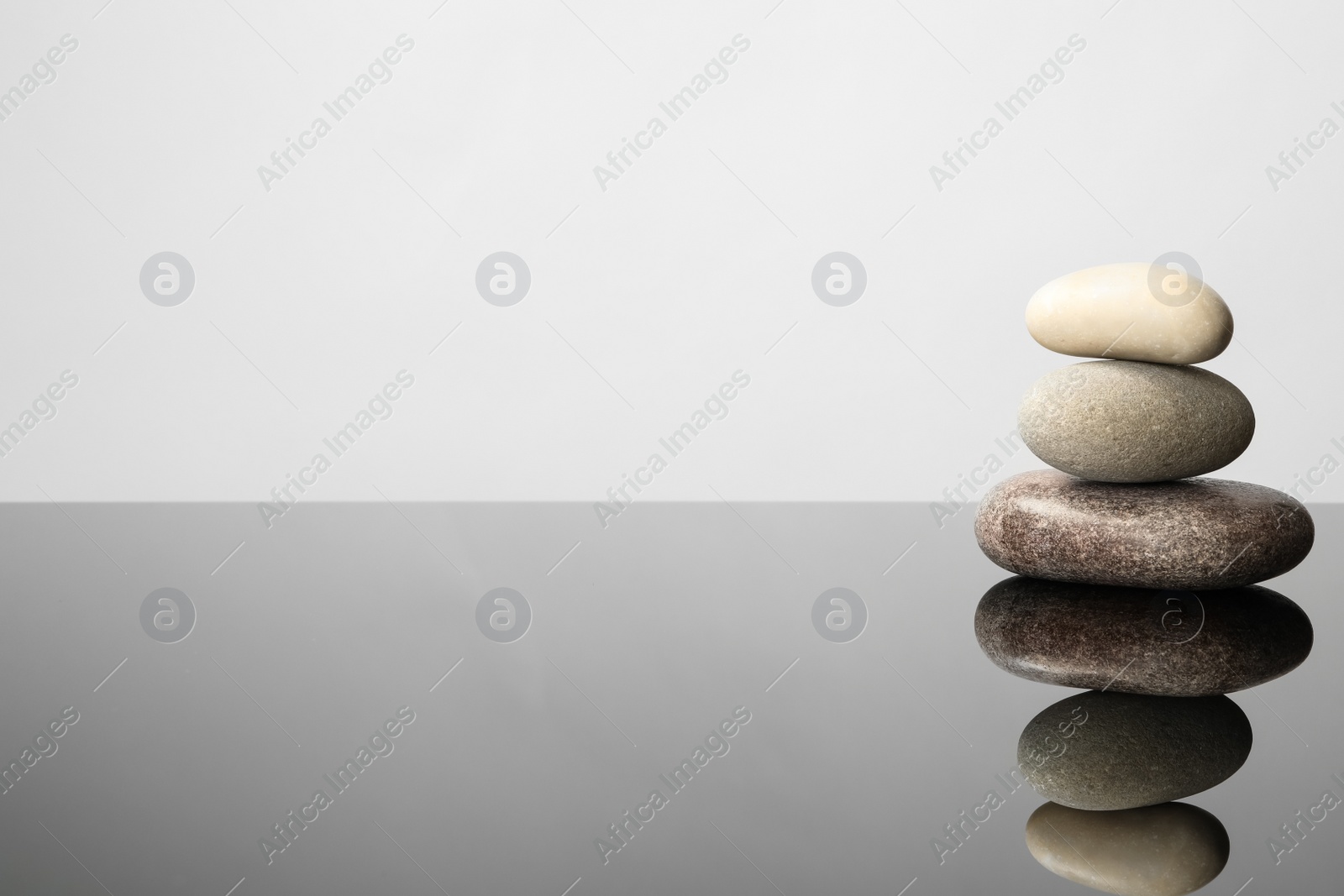 Photo of Stack of spa stones on mirror surface. Space for text