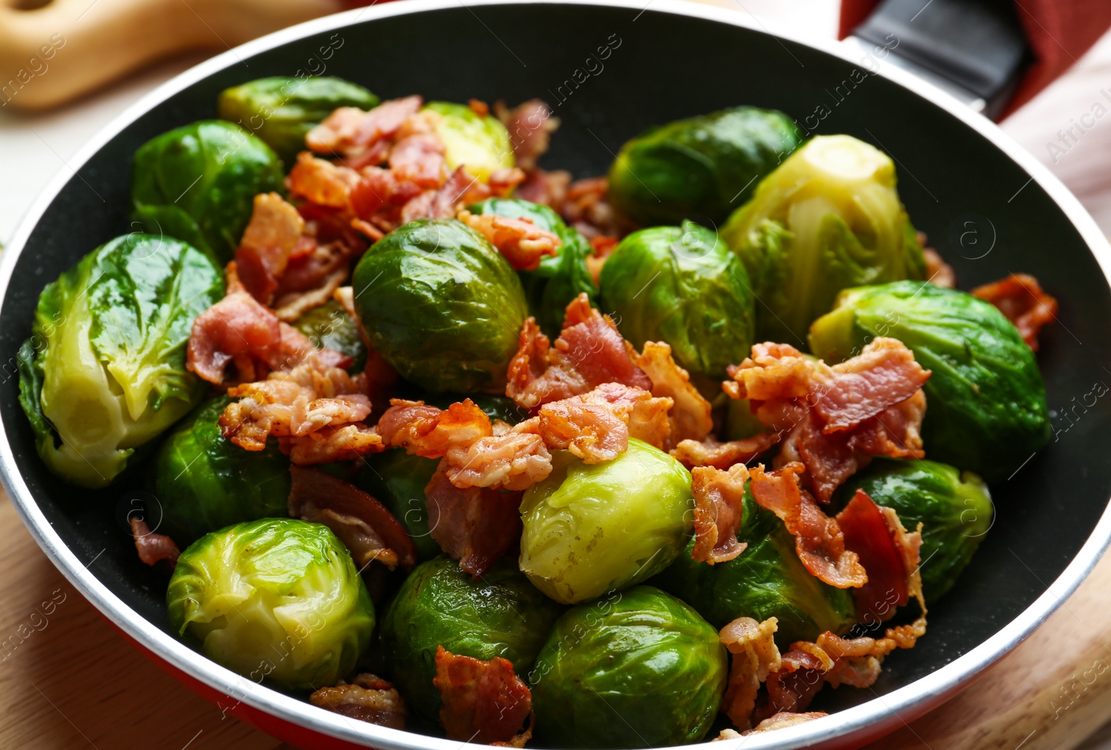 Photo of Tasty roasted Brussels sprouts with bacon in frying pan, closeup