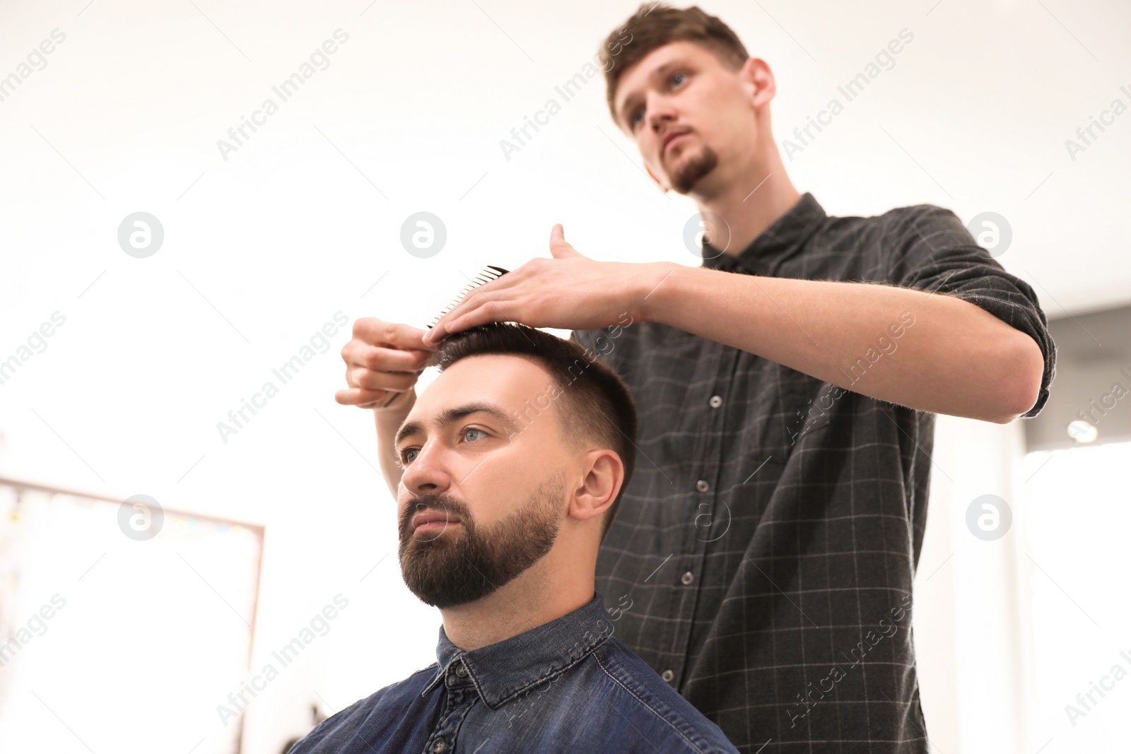 Photo of Professional barber working with client in hairdressing salon. Hipster fashion