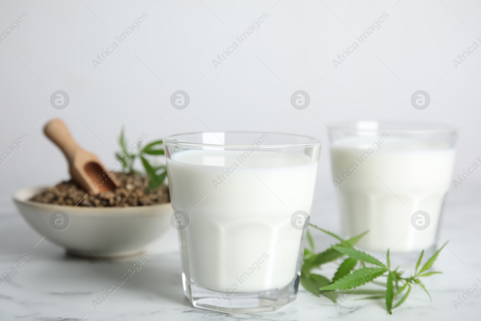 Photo of Hemp milk and fresh leaves on white marble table