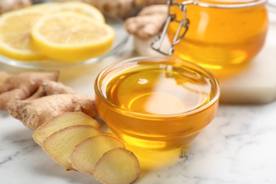 Photo of Honey and ginger on white table, closeup. Natural cold remedies