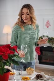 Photo of Young woman setting table for Christmas dinner at home
