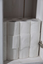Photo of Stacked toilet paper rolls in cabinet indoors