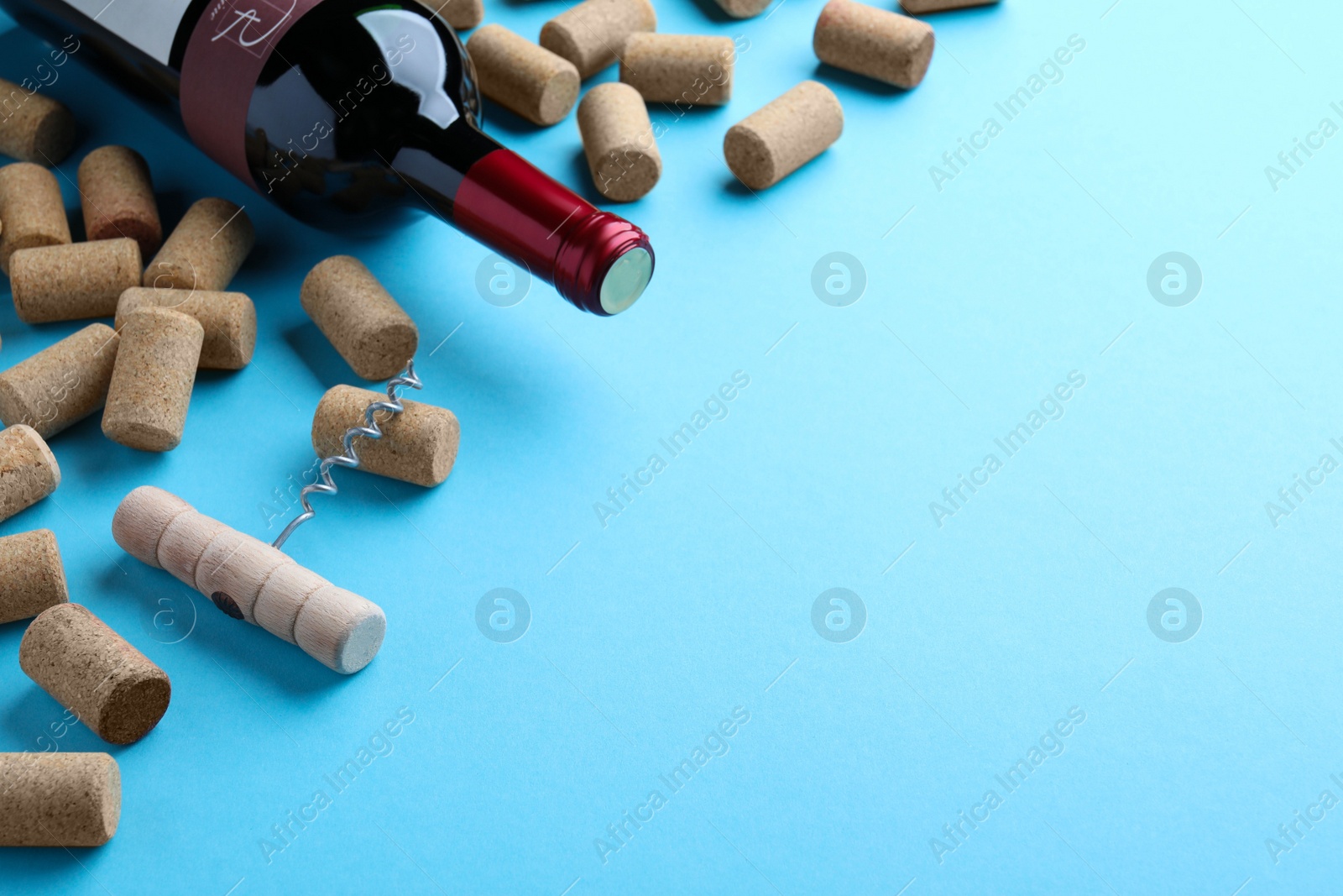 Photo of Corkscrew with wine bottle and stoppers on turquoise background. Space for text