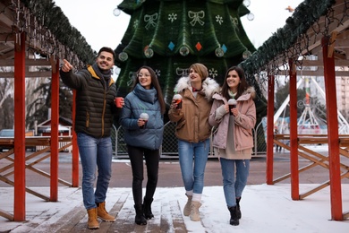 Photo of Friends with cups of mulled wine at winter fair