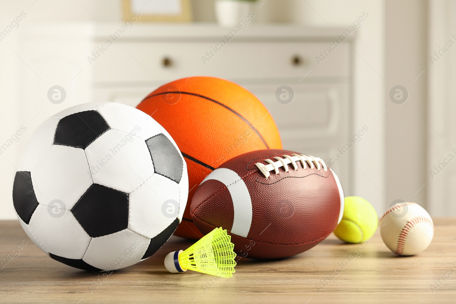 Photo of Set of different sport balls and shuttlecock on wooden table indoors