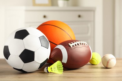 Photo of Set of different sport balls and shuttlecock on wooden table indoors