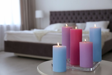 Photo of Burning candles on table in light bedroom