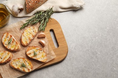 Photo of Tasty bruschettas with oil and rosemary on light grey table, flat lay. Space for text