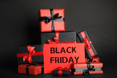 Many gift boxes and sheet of paper with words Black Friday on dark background