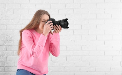 Female photographer with camera on brick background
