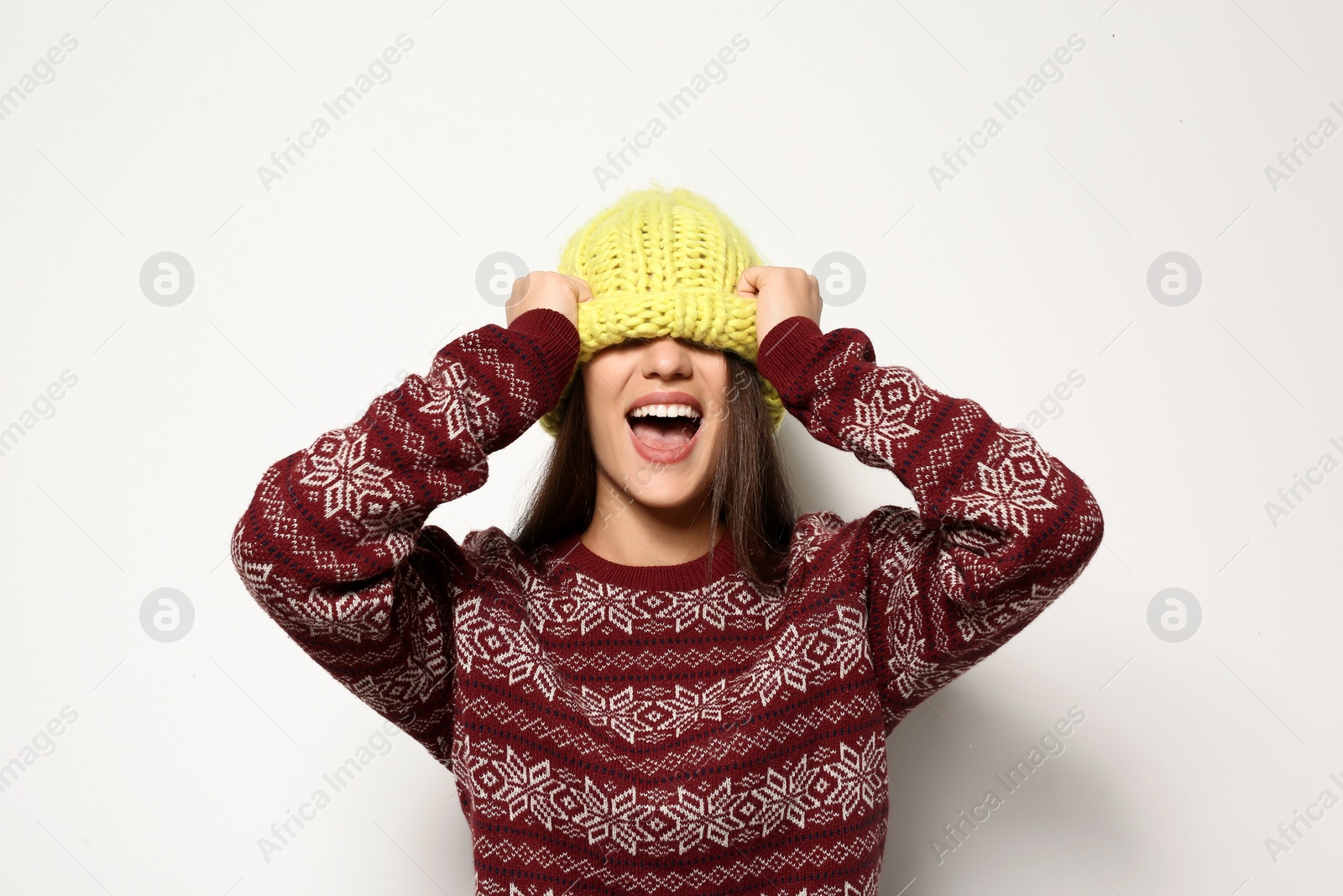 Photo of Young woman in warm sweater and knitted hat on white background. Celebrating Christmas