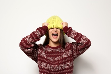 Young woman in warm sweater and knitted hat on white background. Celebrating Christmas