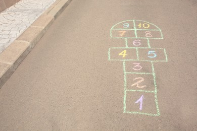 Photo of Hopscotch drawn with colorful chalk on asphalt outdoors. Space for text