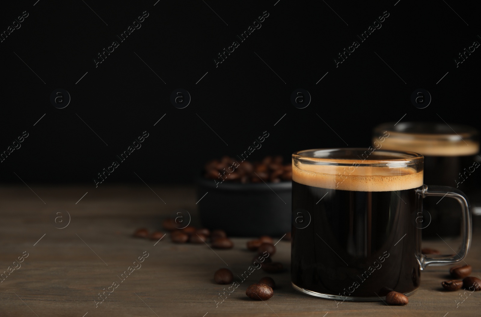 Photo of Cups of hot aromatic coffee and roasted beans on wooden table. Space for text