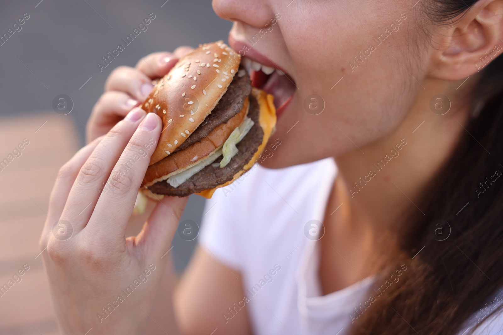 Photo of Lviv, Ukraine - September 26, 2023: Woman eating McDonald's burger outdoors, closeup