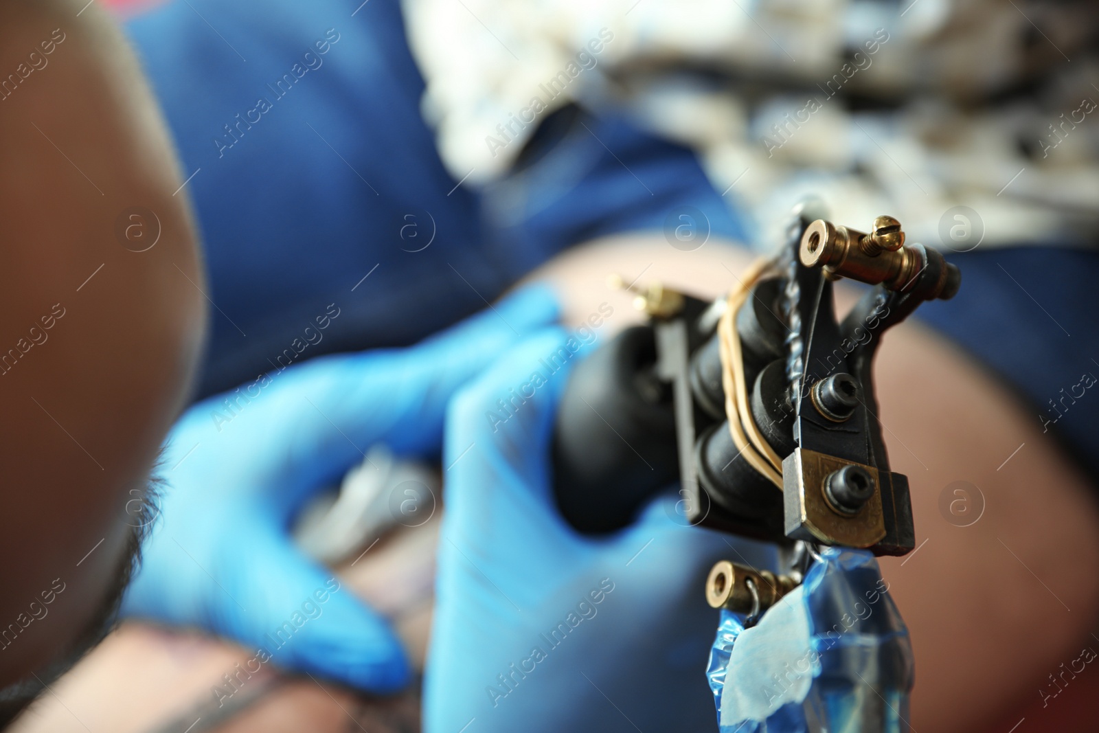 Photo of Professional tattoo artist working with client in salon, closeup