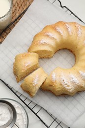 Photo of Delicious sponge cake with powdered sugar and glass of milk on table, flat lay