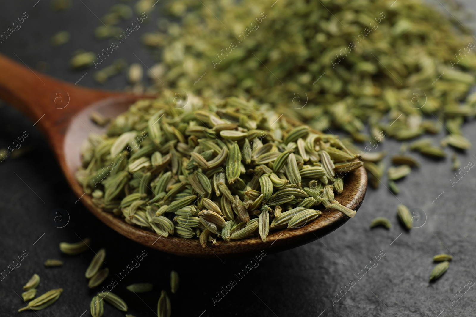 Photo of Spoon with fennel seeds on gray table, closeup