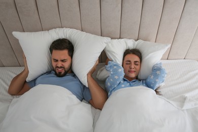 Photo of Young couple suffering from noisy neighbours in bed at home, above view