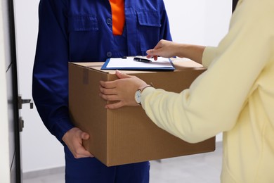 Woman receiving parcel from courier indoors, closeup