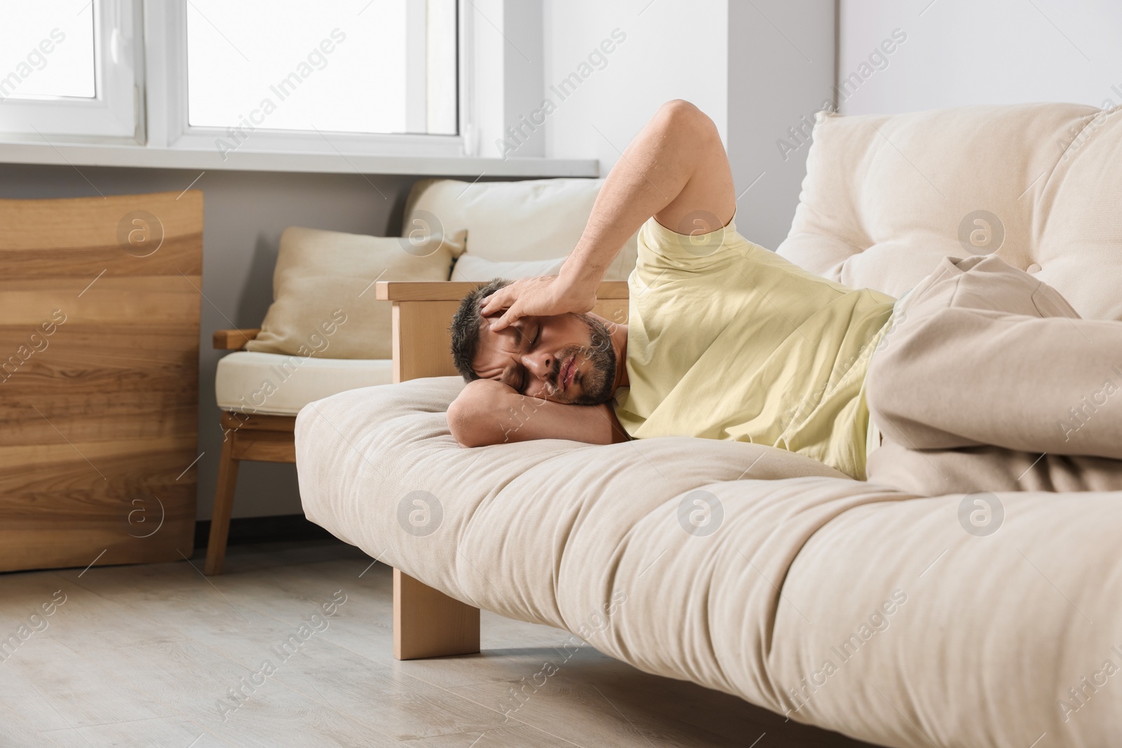 Photo of Sleepless man lying on sofa at home