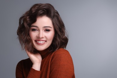 Photo of Portrait of beautiful young woman with wavy hairstyle on grey background