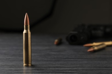 Photo of Bullet on black wooden table. Space for text