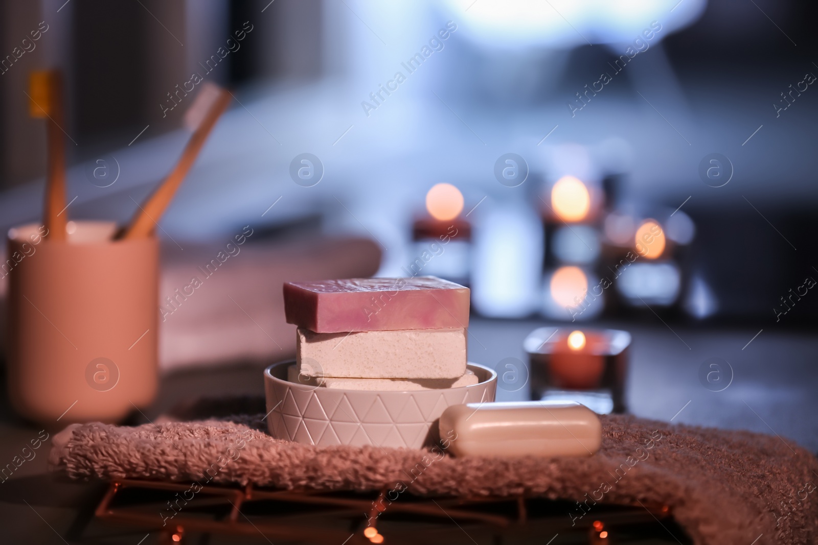 Photo of Soap bars and towel on table against blurred background. Space for text