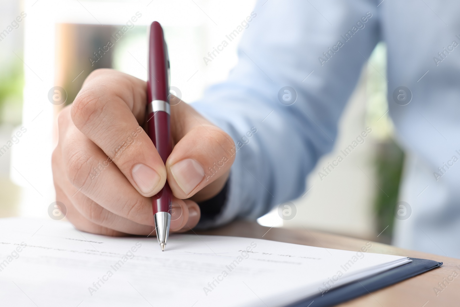 Photo of Man signing contract at table in office, closeup