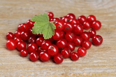 Pile of ripe red currants and leaf on wooden table, closeup