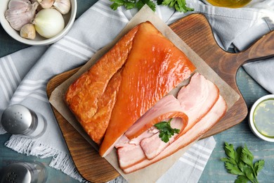 Photo of Flat lay composition with delicious smoked bacon on light blue wooden table