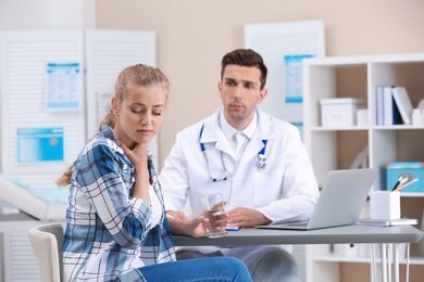Photo of Coughing young woman visiting doctor at clinic