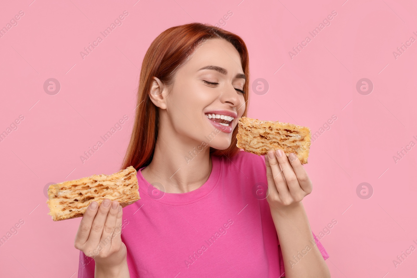 Photo of Young woman with pieces of tasty cake on pink background