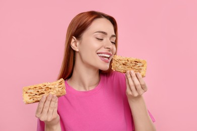 Young woman with pieces of tasty cake on pink background