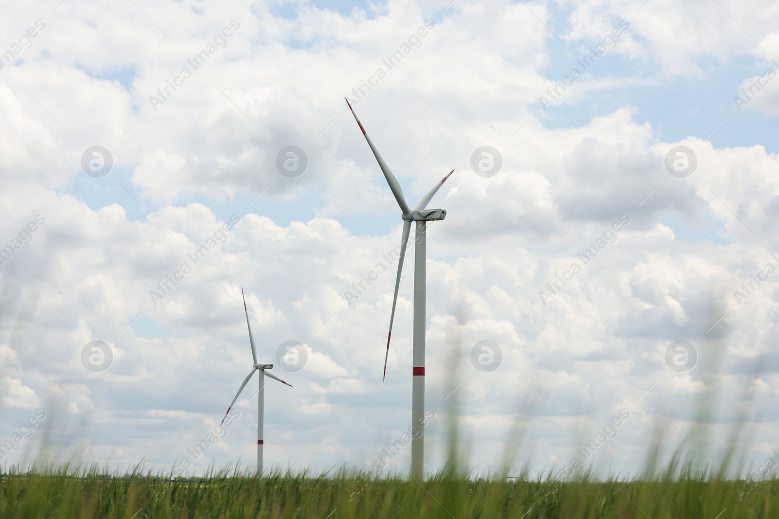 Photo of Modern wind turbines in field on cloudy day. Alternative energy source