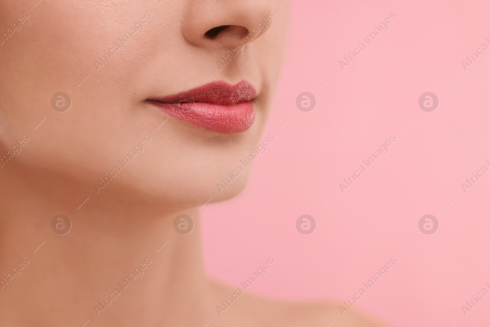 Photo of Woman with beautiful lips on pink background, closeup. Space for text