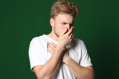 Photo of Handsome young man coughing against color background