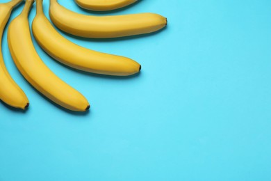 Photo of Ripe yellow bananas on turquoise background, flat lay. Space for text