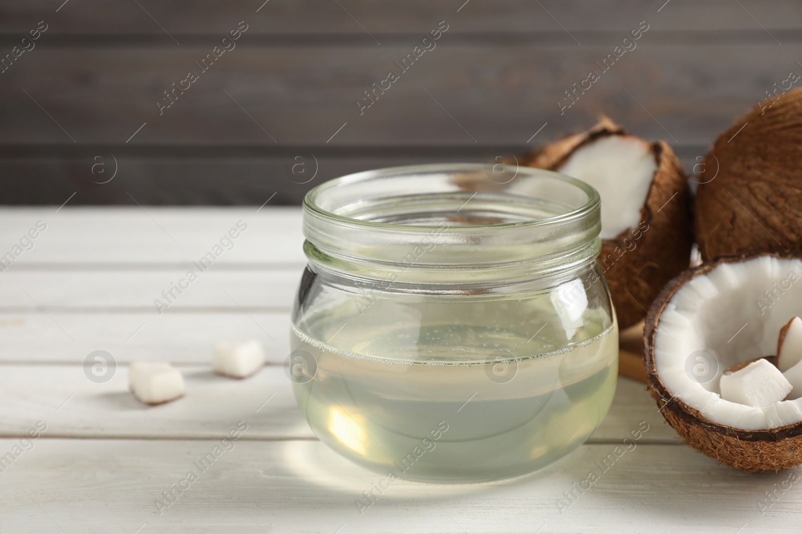 Photo of Coconut oil on white wooden table, closeup