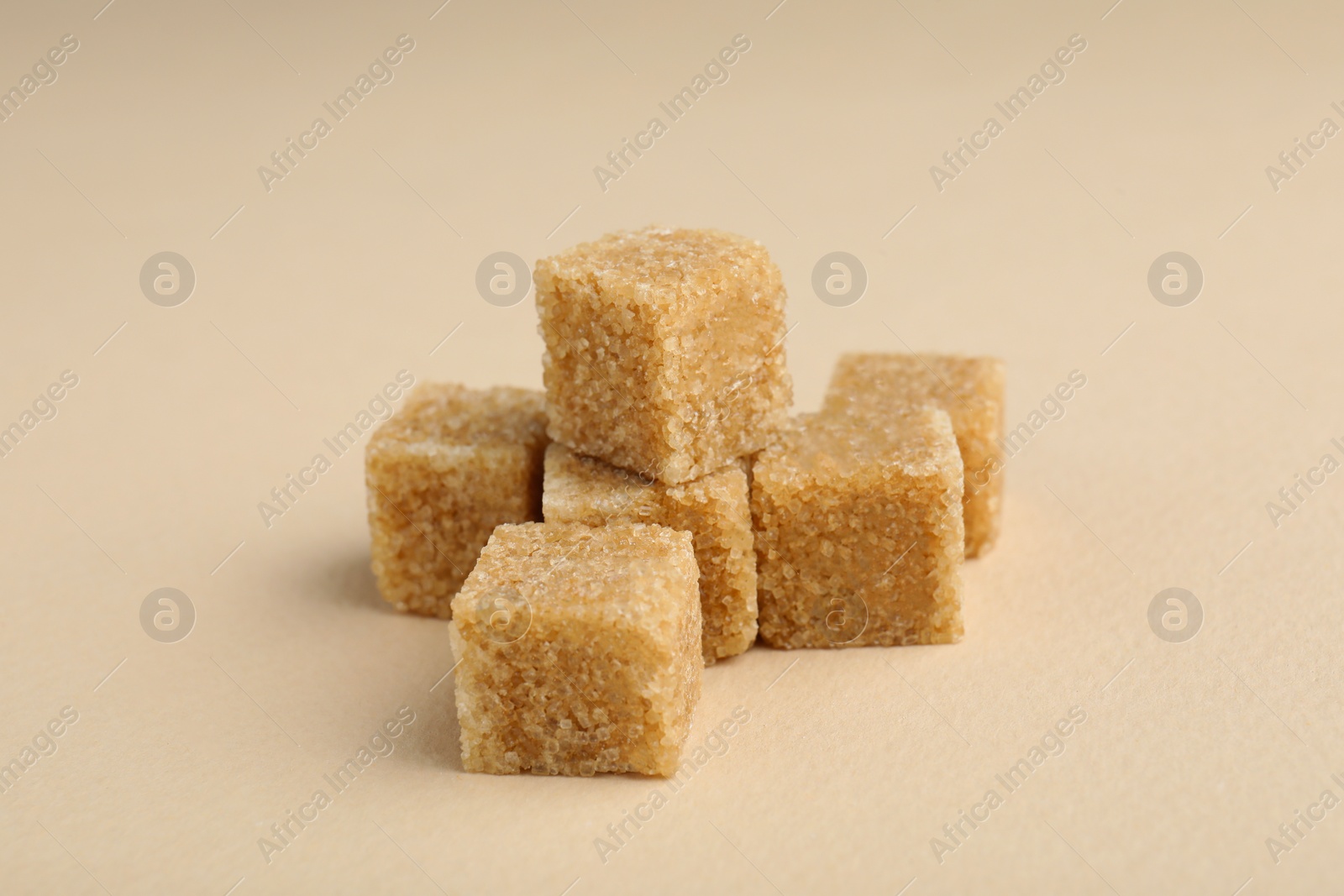 Photo of Brown sugar cubes on beige background, closeup