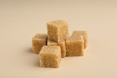 Brown sugar cubes on beige background, closeup