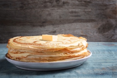 Photo of Plate with thin pancakes and butter on table