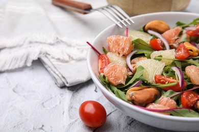 Photo of Delicious pomelo salad with tomatoes and mussels on white textured table, closeup